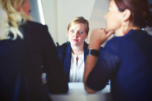 Legal Responsibilities and Continuous Conformity Three people having a discussion at a table in an office setting.