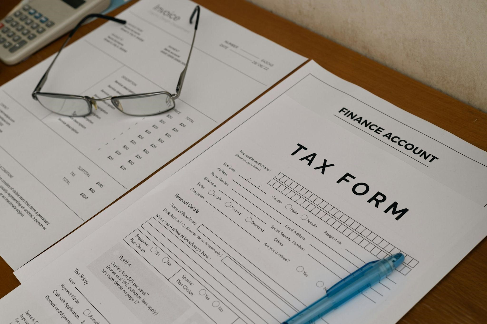 A tax form, pen, eyeglass, and a calculator on a table