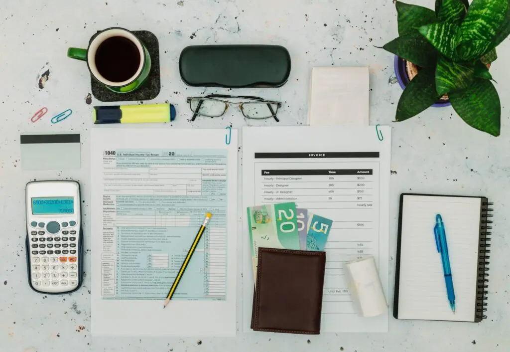 Office desk with tax forms, calculator, glasses, and coffee.