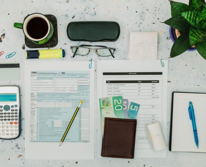 Office desk with tax forms, calculator, glasses, and coffee.