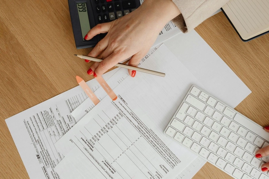 Person reviewing financial documents with a calculator and keyboard on a desk.
