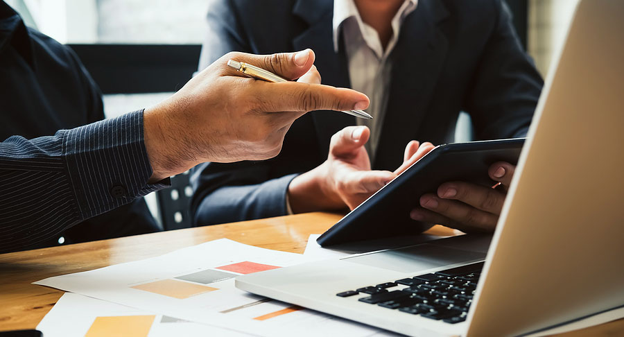 Two people discussing work while using a tablet and laptop