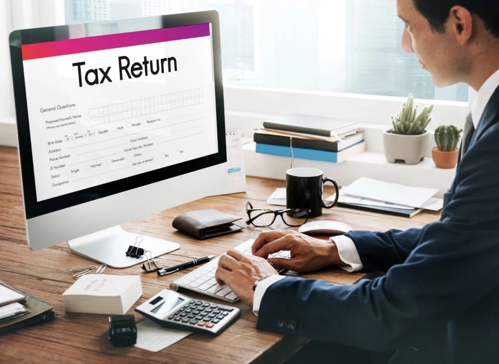 person working on tax return online with calculator and documents