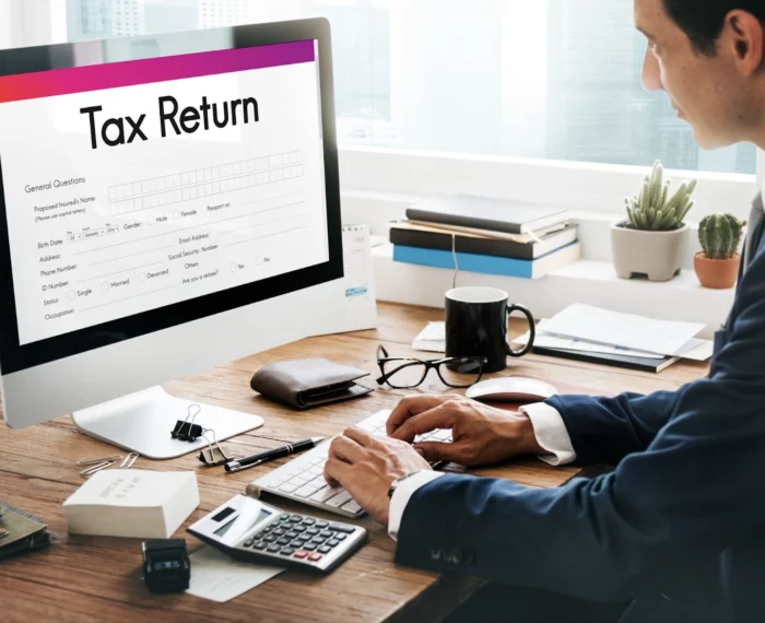 person working on tax return online with calculator and documents