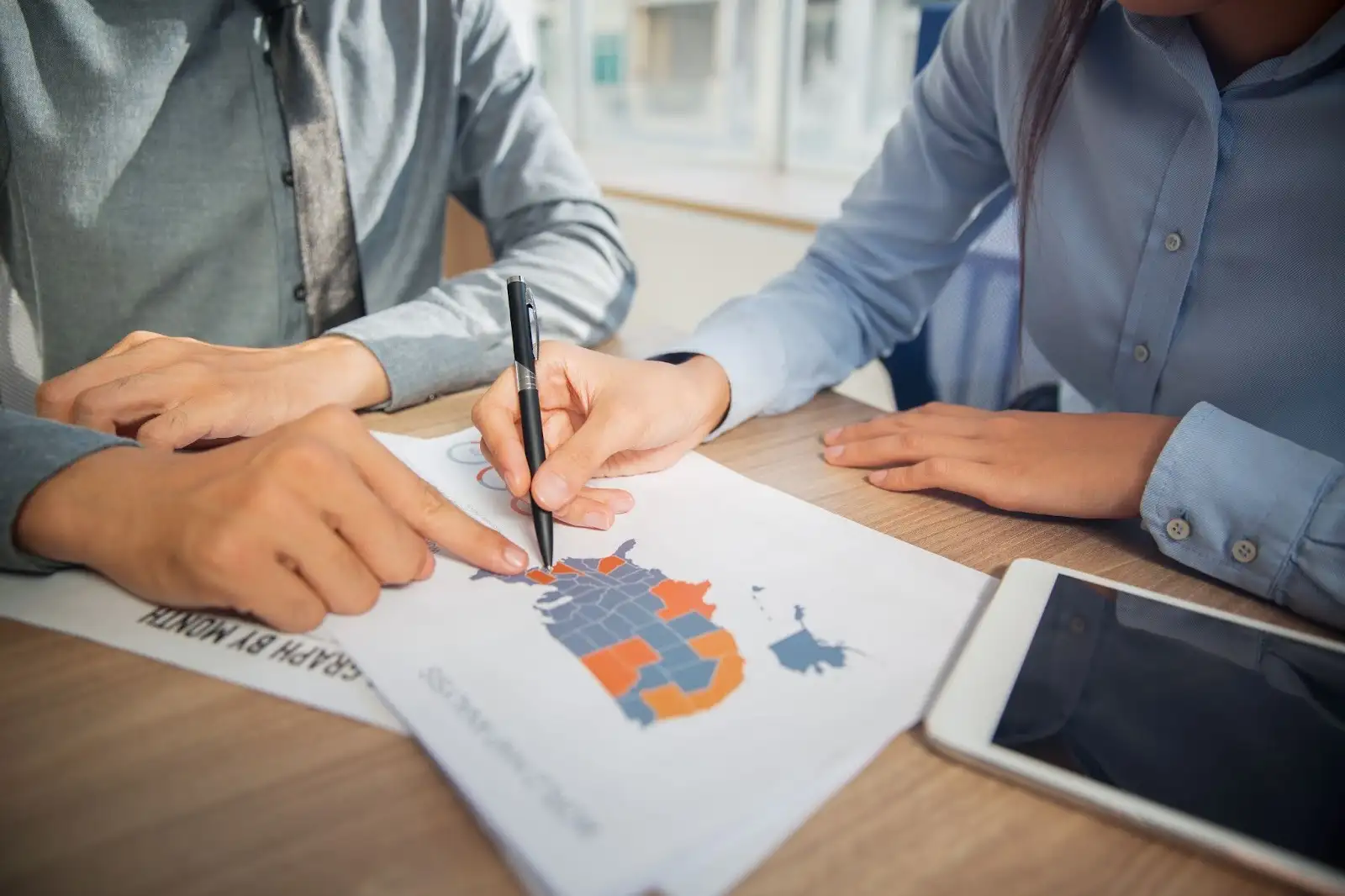 Two corporate employees marking an area on a printed map 